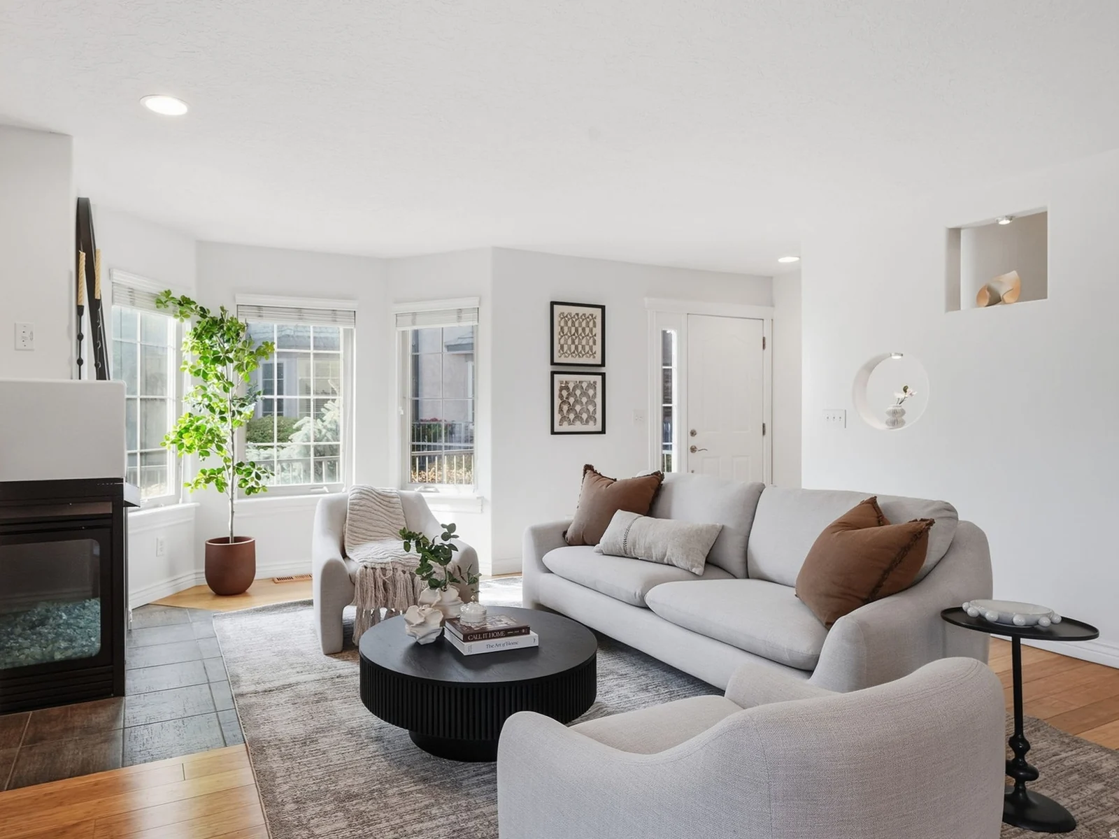 Recessed lighting illuminates this bright living space featuring a bay window, built-in fireplace, and hardwood-finish flooring